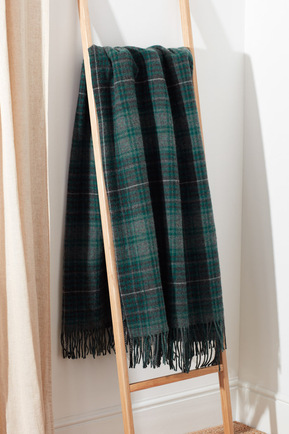 A green tartan wool throw drapped over a wooden towel ladder