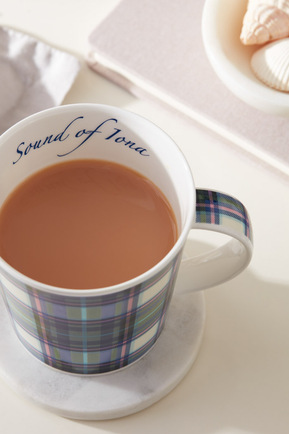 A tea cup shown on a bedside table with a note book and pillow edge