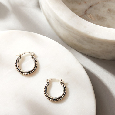 Jewellery photography of silver earrings, minimalist styling with a white marble jewellery box.