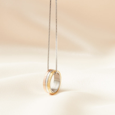 Modern jewellery photography of a gold ring necklace on a neutral fabric