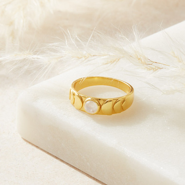 Jewellery photography of a gold ring on a white marble background with white pampas grass
