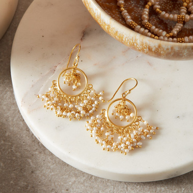 Boho gold pearl earrings on a white marble jewellery box