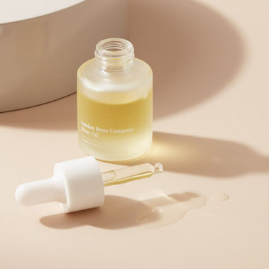 Beauty product photography for a brow oil with swatch on a beige background