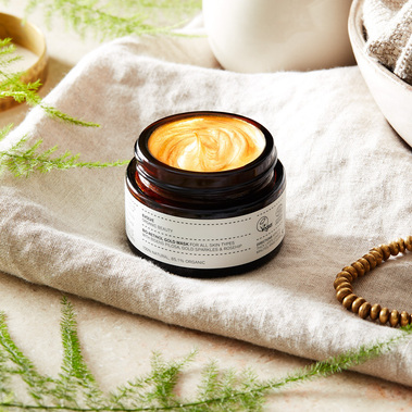Beauty product photographer Sally Williams photographs a skincare jar on a linen background with fresh foliage props.