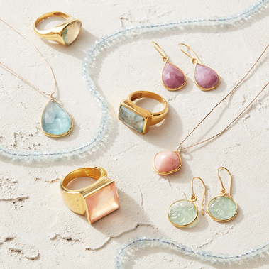 Jewellery photography, gold rings and earrings on a textured neutral background.