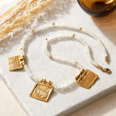 Product photography by Sally Williams of a boho gold necklace on stone background with dried grasses