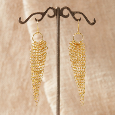 Boho gold dangly earrings on a rustic display stand with a natural colour linen background