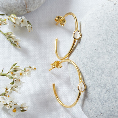 Boho jewellery photography of gold and diamond earrings on a white linen and stone background