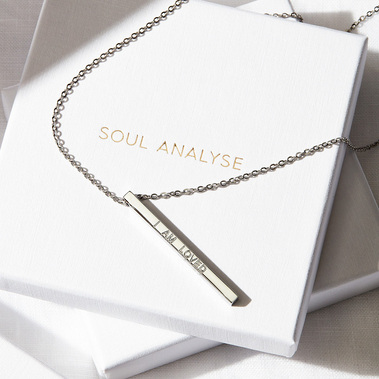 Jewellery photographer UK.  Necklace on white boxes, minimalist style with shadows.