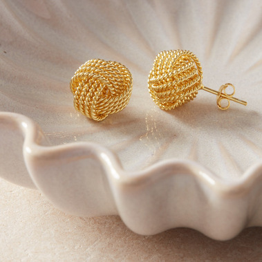 Gold stud earrings on a flower shaped trinket bowl