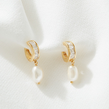 Minimalist jewellery photography of gold earrings on a white cotton background