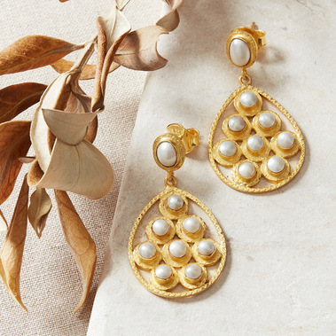 Boho jewellery photographer, styled gold earrings with dried leaves and a natural stone background