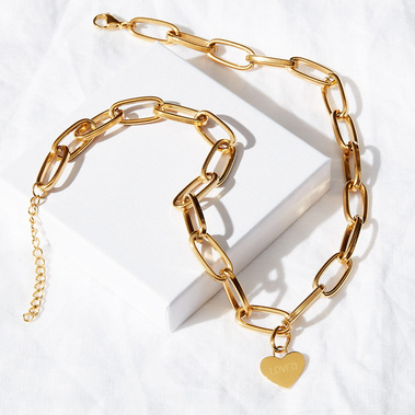 Product photography of a gold necklace on a white linen background with hard shadows 