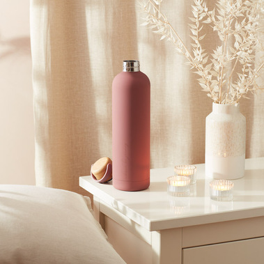 Water bottle on a bedside table in beige tones in dappled sunlight