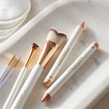 Cosmetics photography, make up brushes and concealer pencils on a white marble tray
