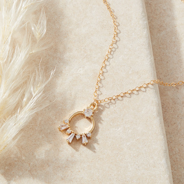 Jewellery photography of a gold pendant necklace on a beige stone background