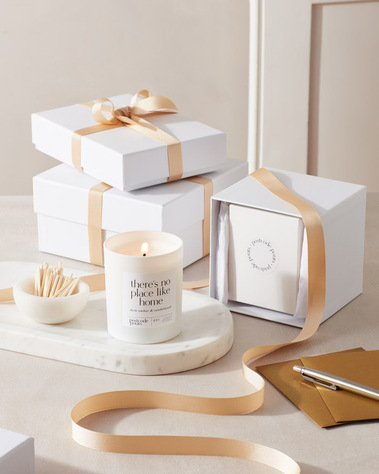 Product photography of a scented candle with gift box and ribbon and matches