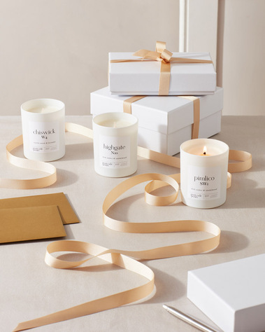 Product photography of a scented candle with gift boxes and gold ribbon