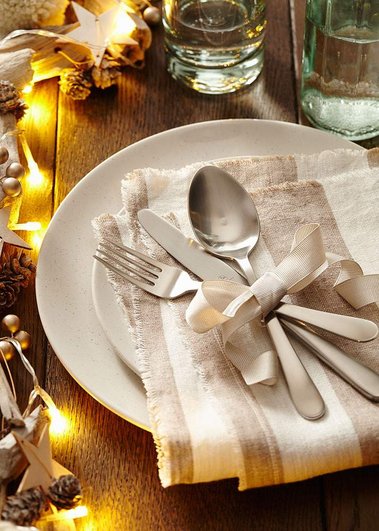 Christmas product photography of a dinner table setting with plate cutlery and fairy lights with decorations