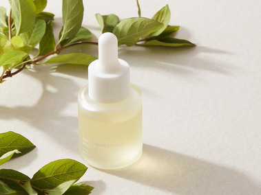 Skincare product photography, bottle with botanical ingredients on a neutral off white background