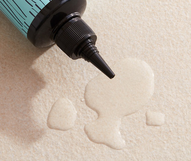 Haircare product photography of a hair loss treatment pooling out of a nozzle