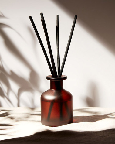 Lifestyle product photography of a diffuser on  tabletop in a dappled leaf shadow