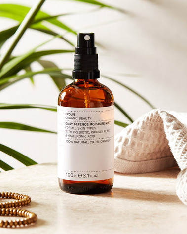 Lifestyle product photography of a skincare product on a beige stone background with a palm plant. 