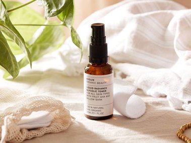 Beauty product photographer uk. Evolve organic beauty skincare bottle styled with linen and fresh foliage.