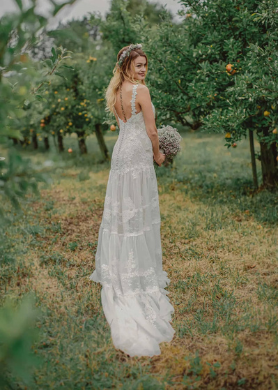 Brautportrait in der Natur in einem Vintage Happy Hochzeitskleid und Blumenkranz auf dem Kopf auf einer schöner Brautfrisur 