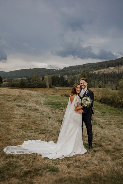 Hochzeitspaar auf einer breite Wiese mitten im Wald und die Braut trägt ein schlichtes Kleid mit offenem Rücken 