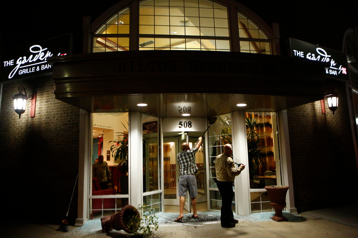 CHARLOTTE, NC - SEPTEMBER 21: A crew works to remove broken glass from the front entry of the Hilton Garden Inn after rioters made their way through the area bashing glass and looting businesses while protesting the death of Keith Scott September 21, 201