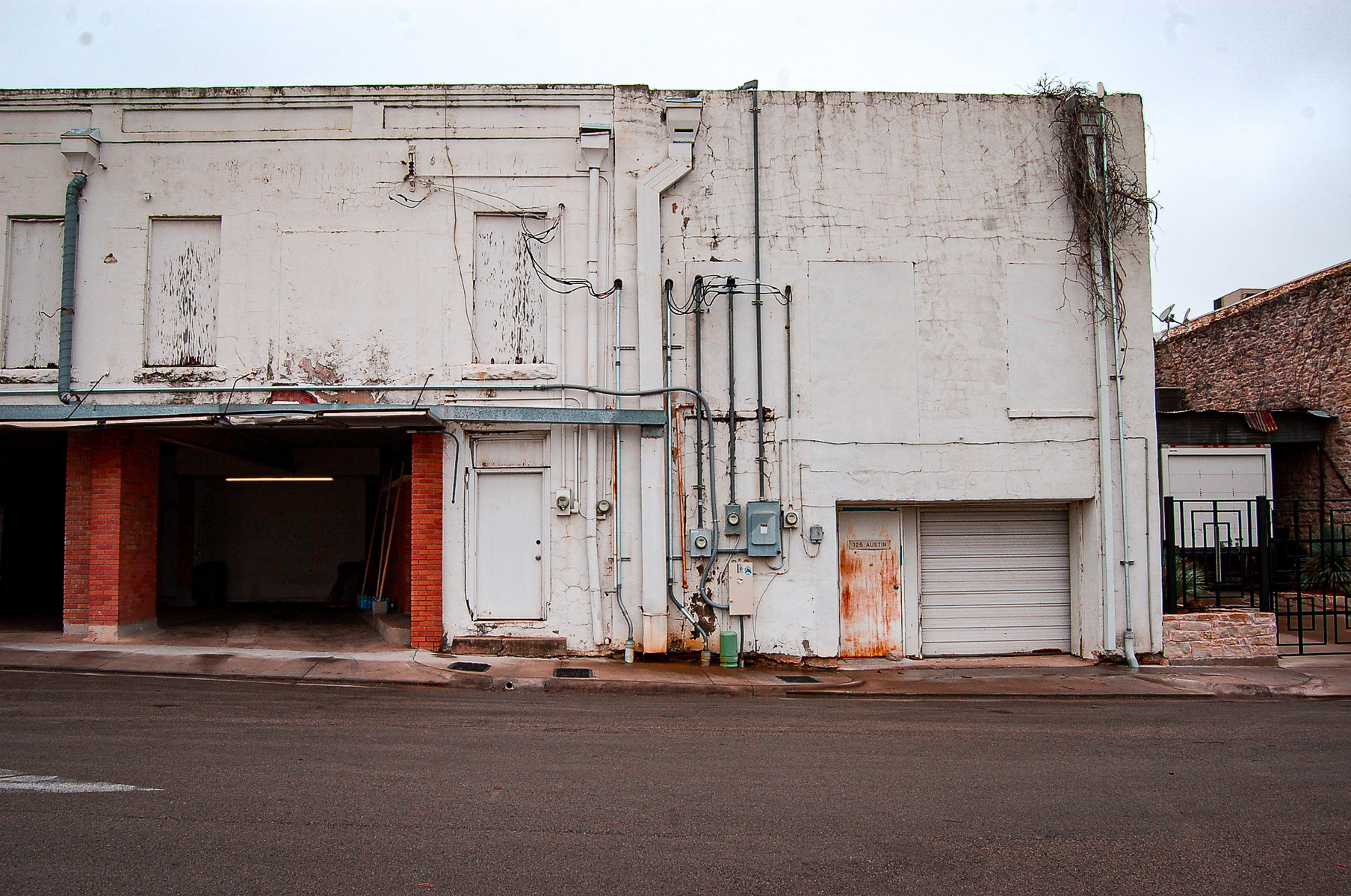 There’s chaos in the quiet. Rust stains, tangled wires, utility boxes — all whispering of the human systems behind the scenes. The building still holds its ground even as it falls apart.