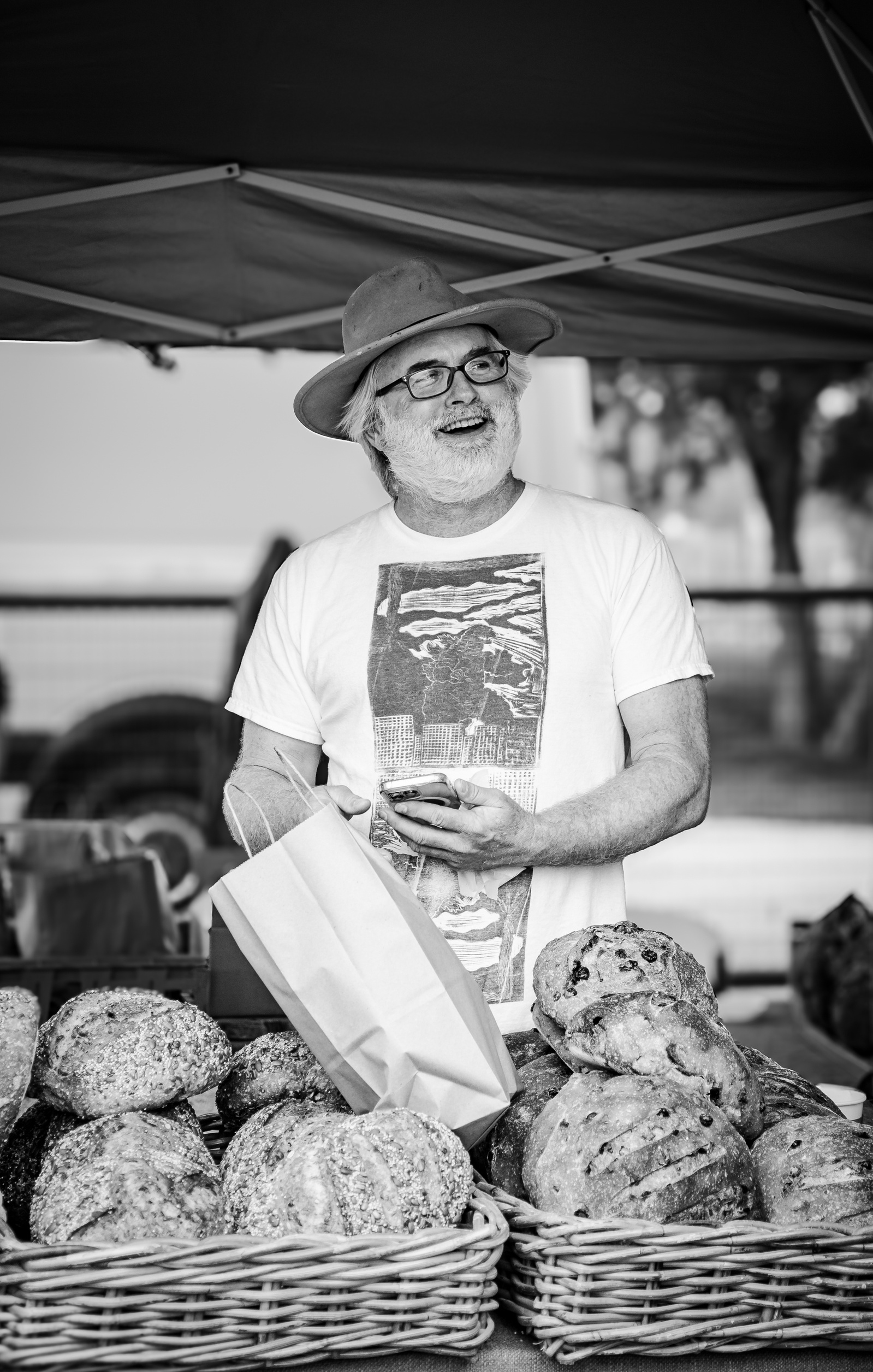 The weight of years sits lightly on him, flour-dusted hands in motion, face caught mid-story. Here, the threshold is warmth—where labor meets laughter, and bread is both currency and connection.