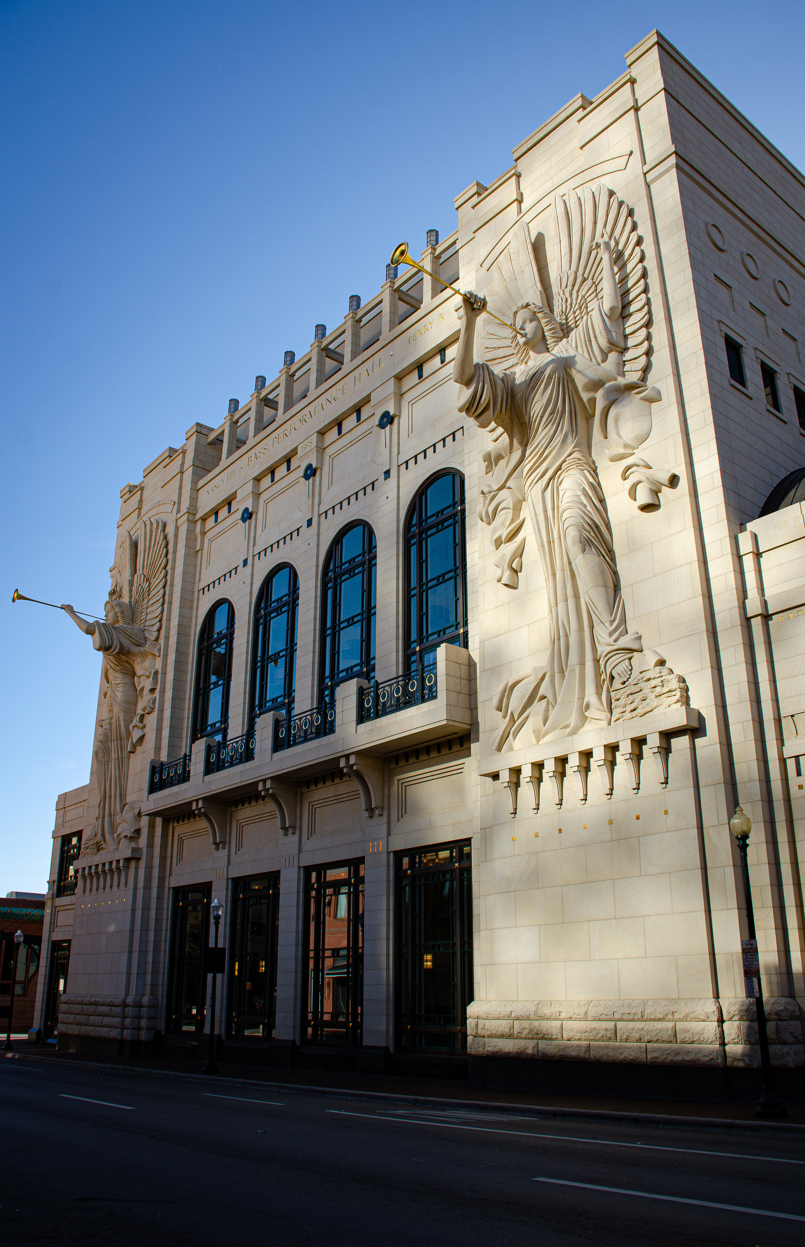 Massive carved angels trumpet into the blue morning sky. Frozen in alabaster, they watch over an empty street that feels caught between theatre and cathedral.