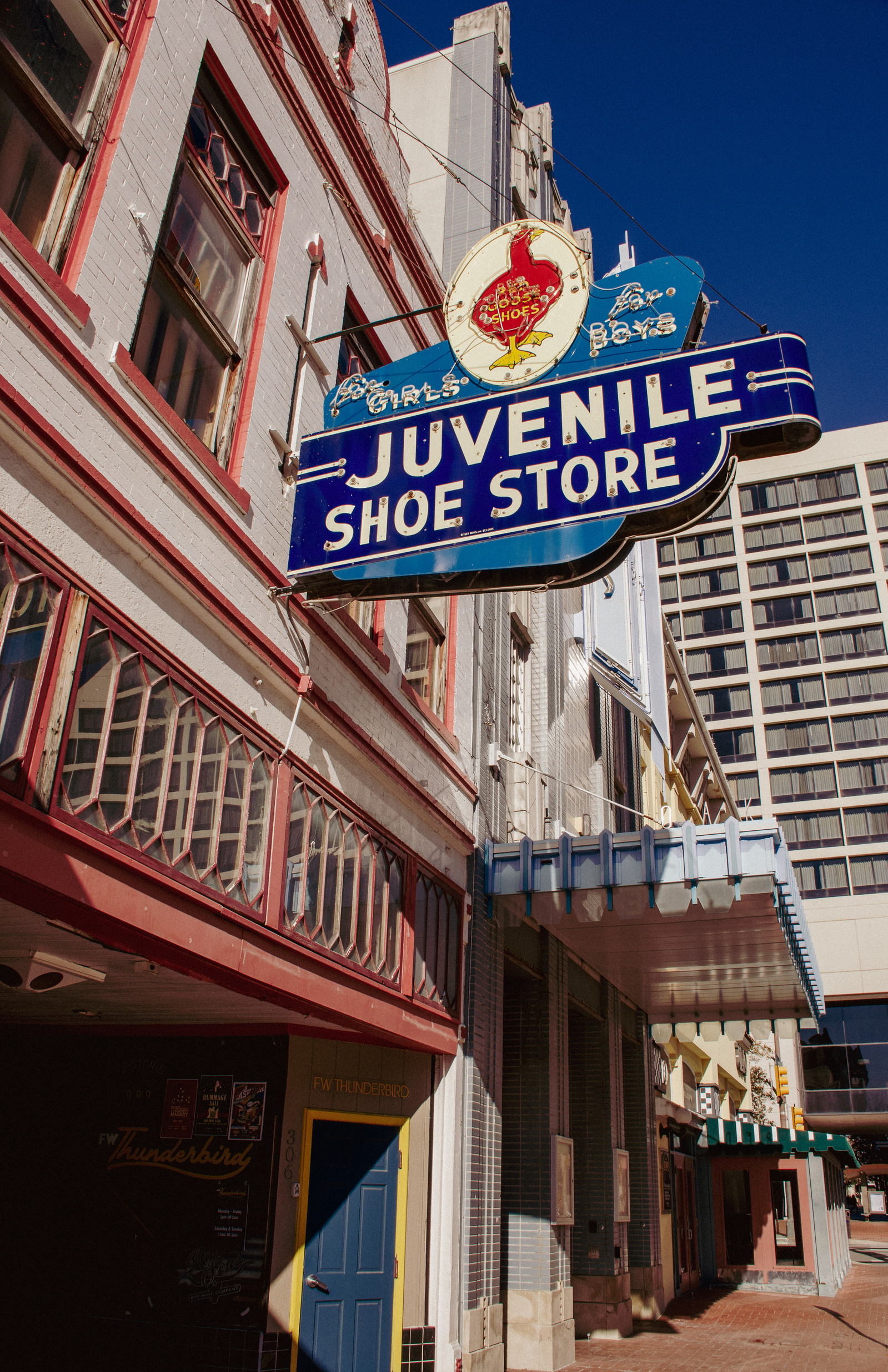 The Juvenile Shoe Store sign, still bold in blues and reds, hovers over shuttered doors—an echo of shopping trips and back-to-school days gone by.