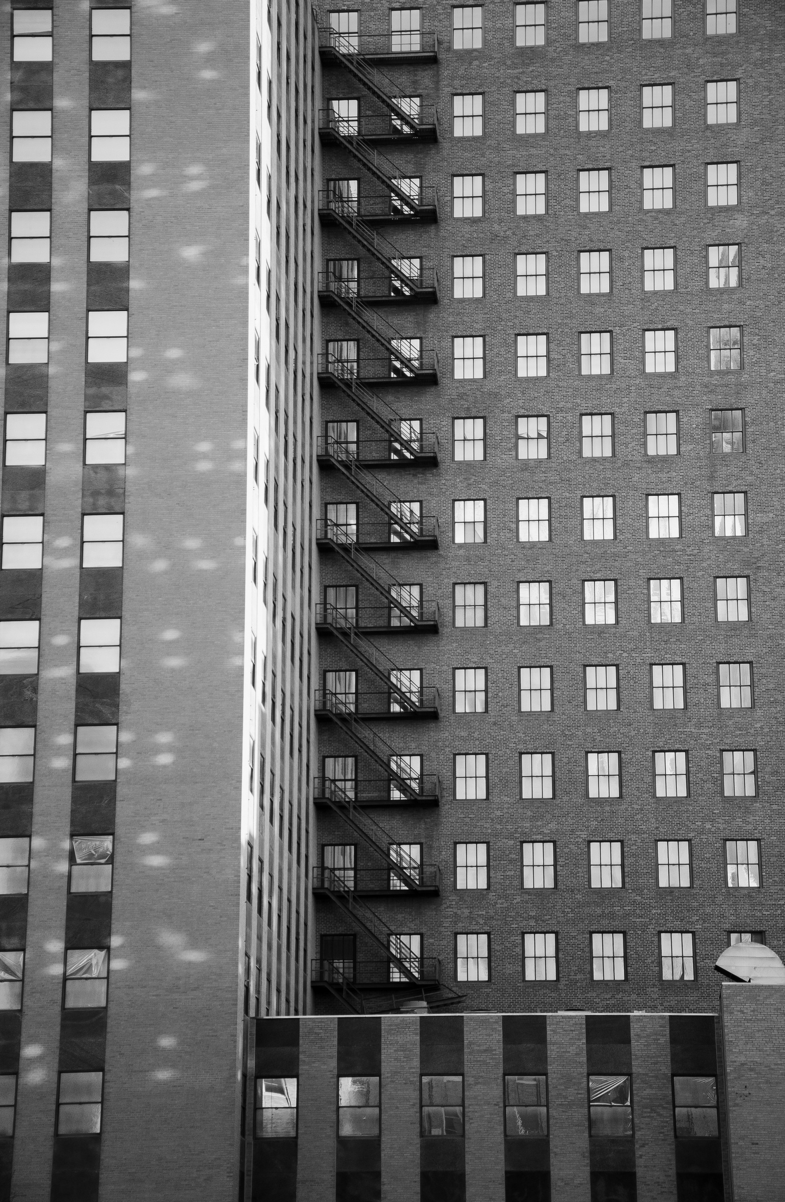Fire escapes draw stair-stepped thoughts down the spine of repetition. Windows mirror windows, a pattern that holds and releases like breath. Here, logic is architectural—and emotional.