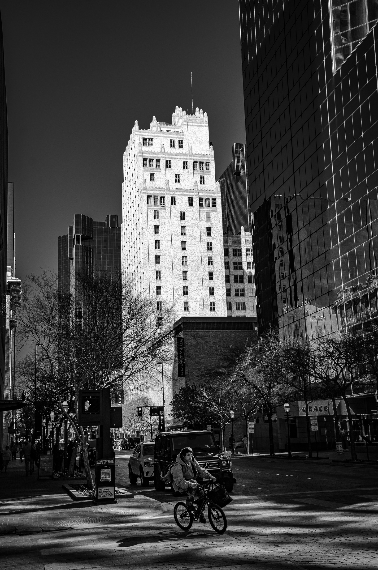 A cyclist cuts across the hush, threading through shadows taller than memory. Amid towering glass and stone, movement becomes defiance. A pulse where the city exhales.