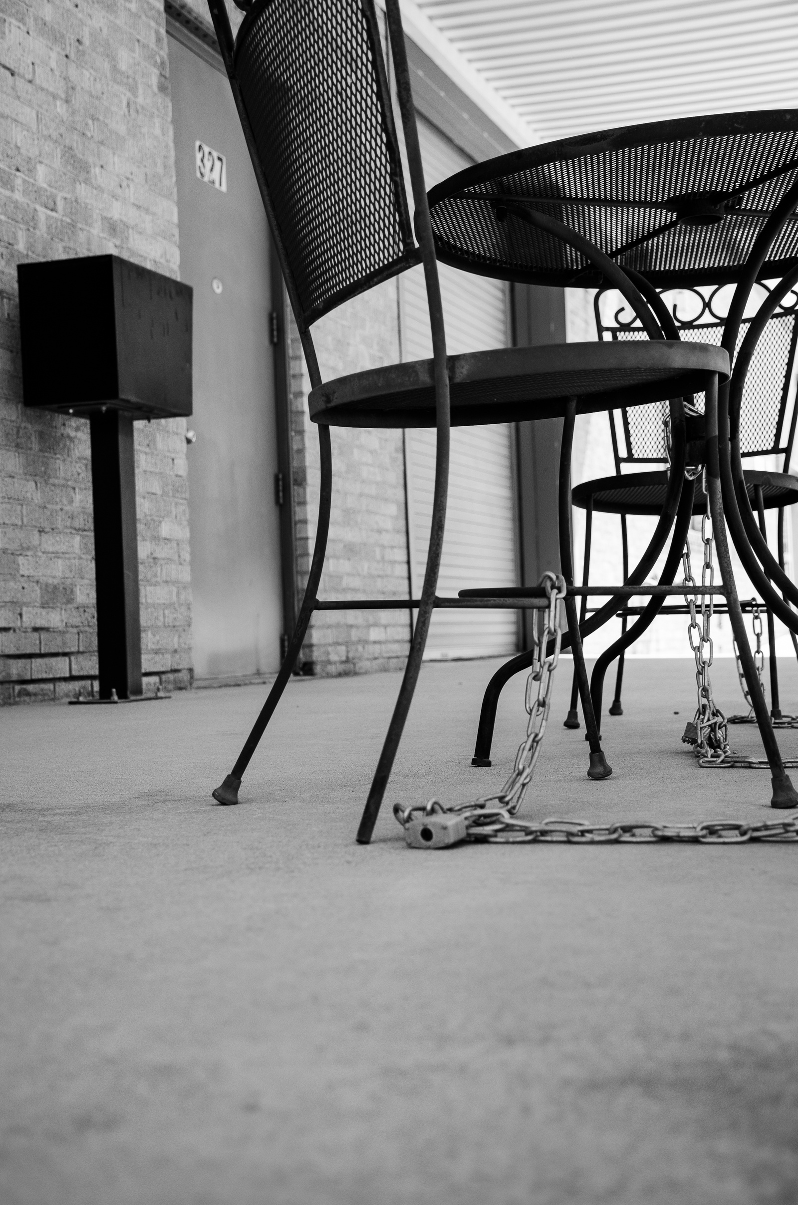 What’s more telling—the absence of people or the presence of locks? This tableau of tethered furniture is less about theft and more about tension. Anchored to safety, but emptied of use.