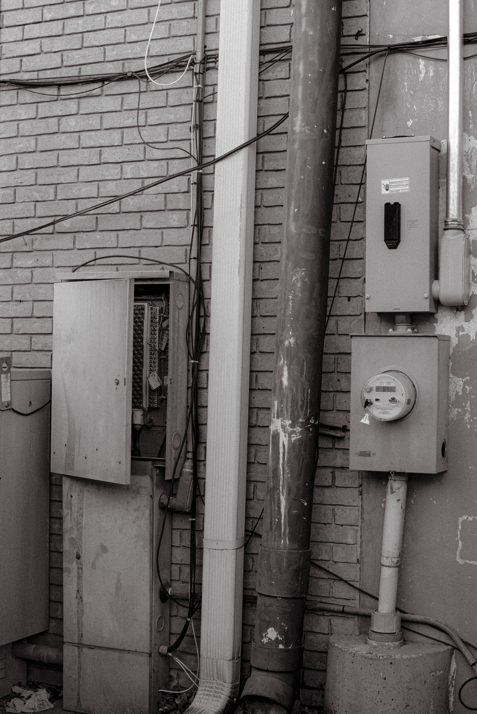 Cables, boxes, rust—this composition is a tangle of utility and decay. The soft monochrome casts an intimate light on the forgotten mechanics that keep our cities pulsing.