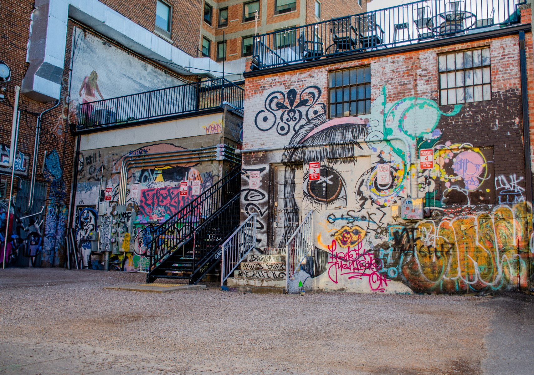 A pair of eyes emerges from layers of street art, creating a powerful presence in this urban canvas. The detailed artwork transforms industrial walls into an immersive experience, where scale and skill combine in a statement of artistic purpose.
