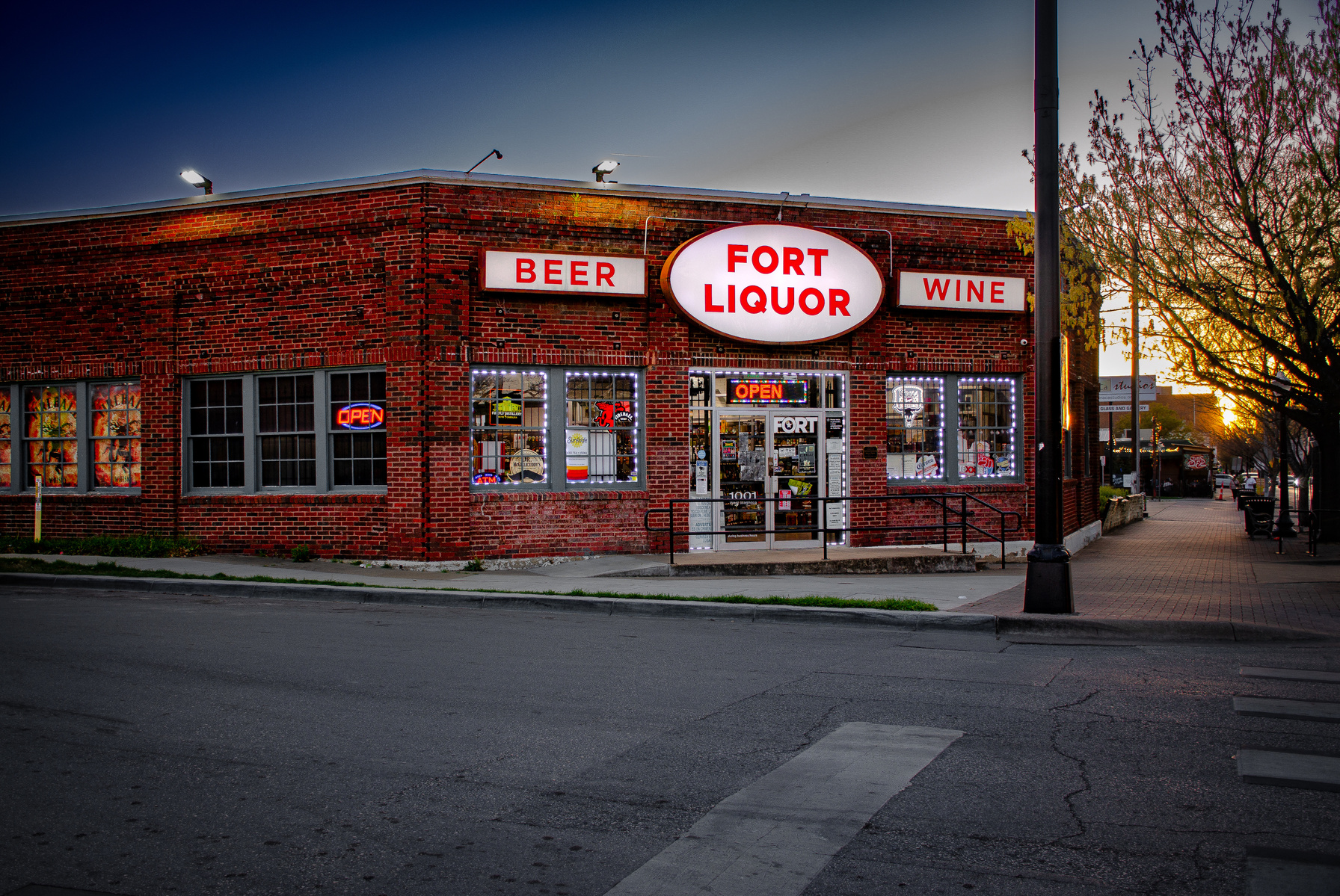 The neon’s promise flickers against dusk. Fort Liquor, a shrine of small escapes and bright signs that outshine the sky.