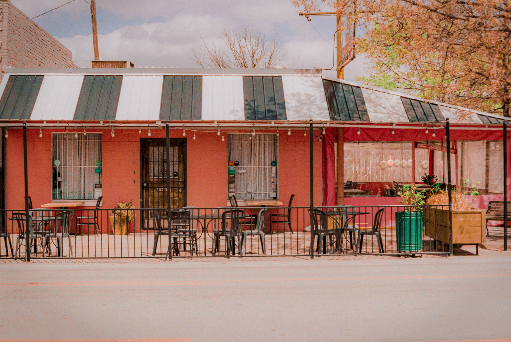 The patio waits—empty chairs echo the slow hours between lunch and dinner. Washed in a dusty warmth, this moment captures a lull that feels both nostalgic and ongoing.
