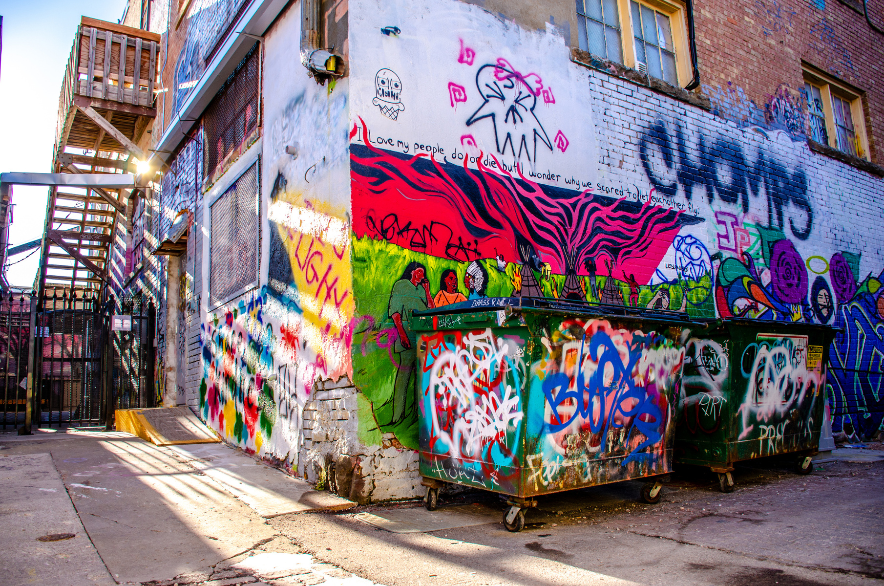 Vibrant street art emerges from shadowed alleyways, where layers of graffiti tell stories of urban expression. The dramatic interplay of bold colors against weathered walls captures the raw energy of street culture.
