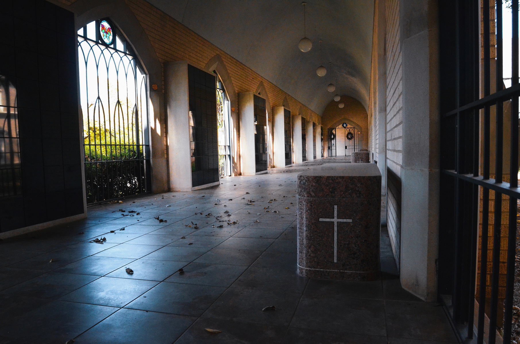 This corridor speaks in shadow and symmetry. A columbarium lined with absence, where the air feels thicker and the silence, sacred.