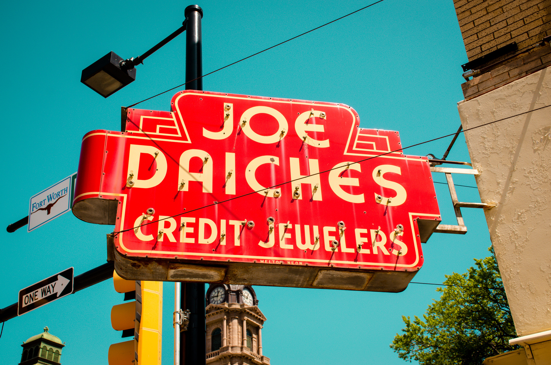A weathered sign shouts into the blue—a Fort Worth classic selling credit and dreams in bold red enamel.