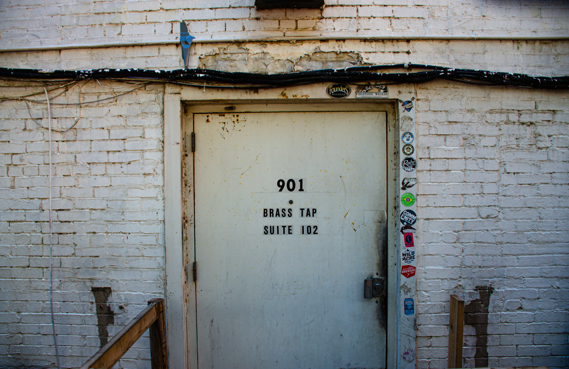 A door without welcome. Layers of grime, a border of brewery stickers, and a lock that says this isn't for you.