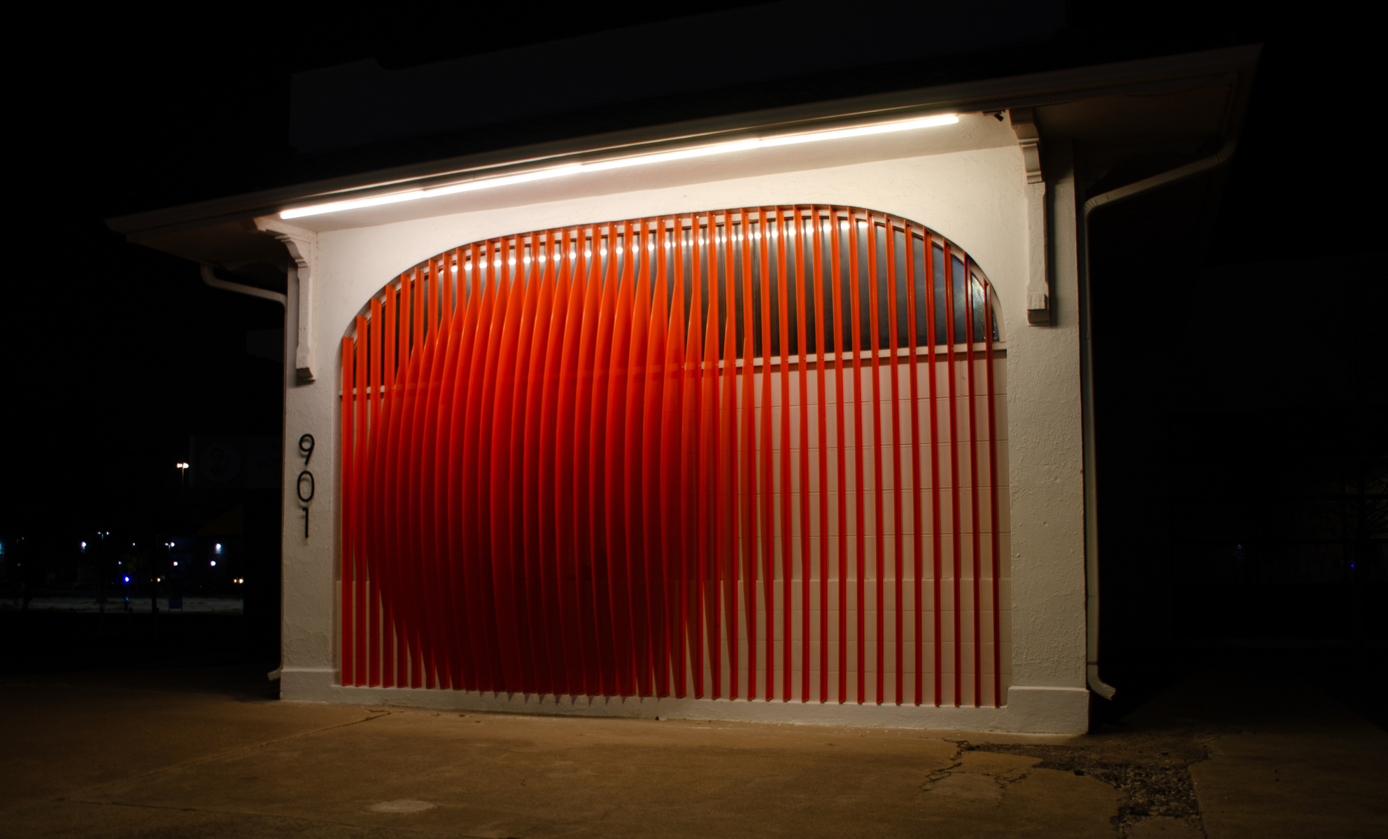 Bending light, rigid lines. A red ripple carved from steel and shadow, this façade hums in perfect silence.