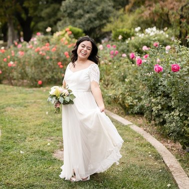 A joyful bride twirls in the McKinley Rose garden of Sacramento, captured with an inclusive wedding photography style that highlights natural beauty, soft florals, and candid, carefree moments.